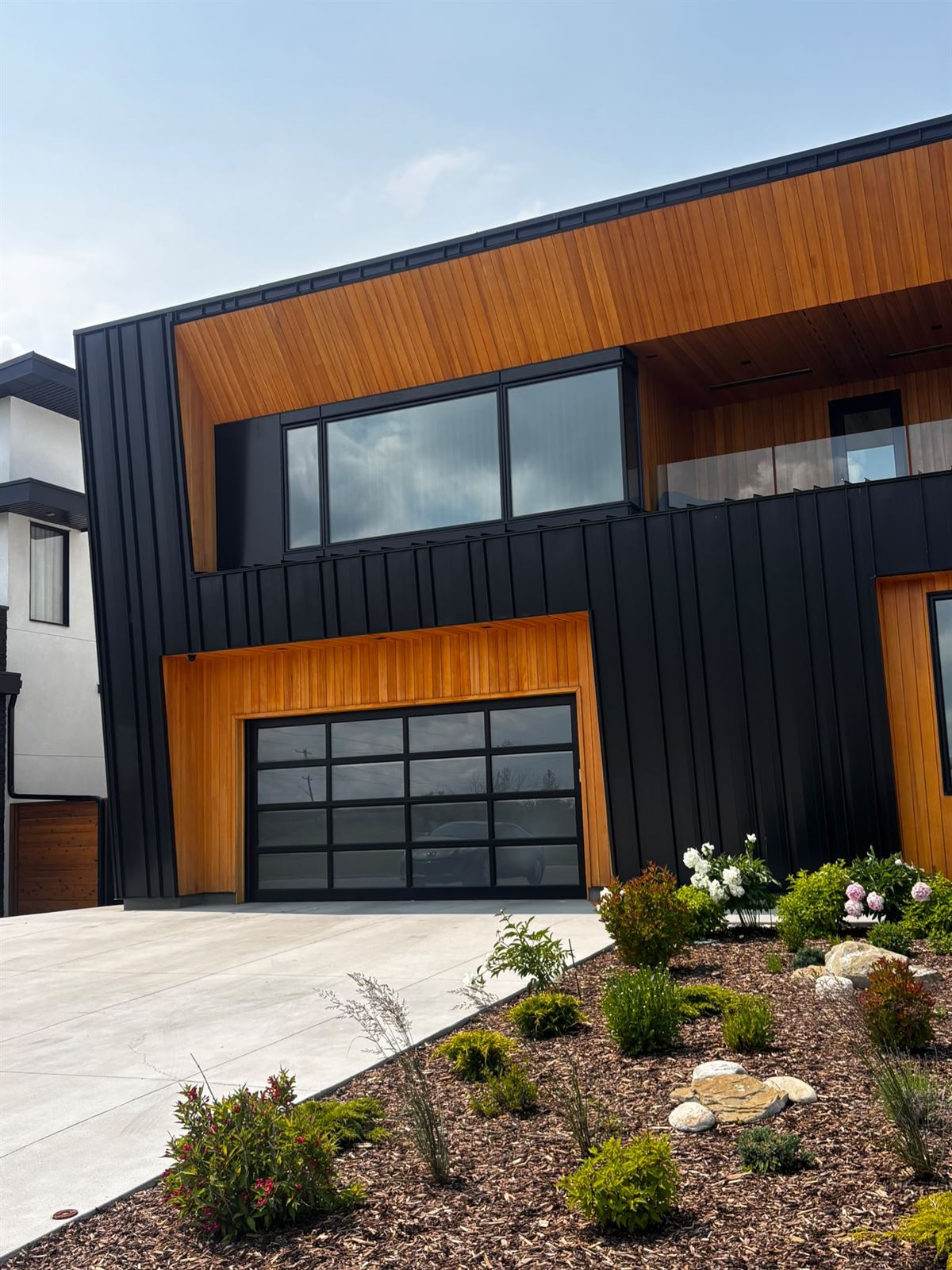Metal siding, cedar accents and a glass garage door on a modern exterior