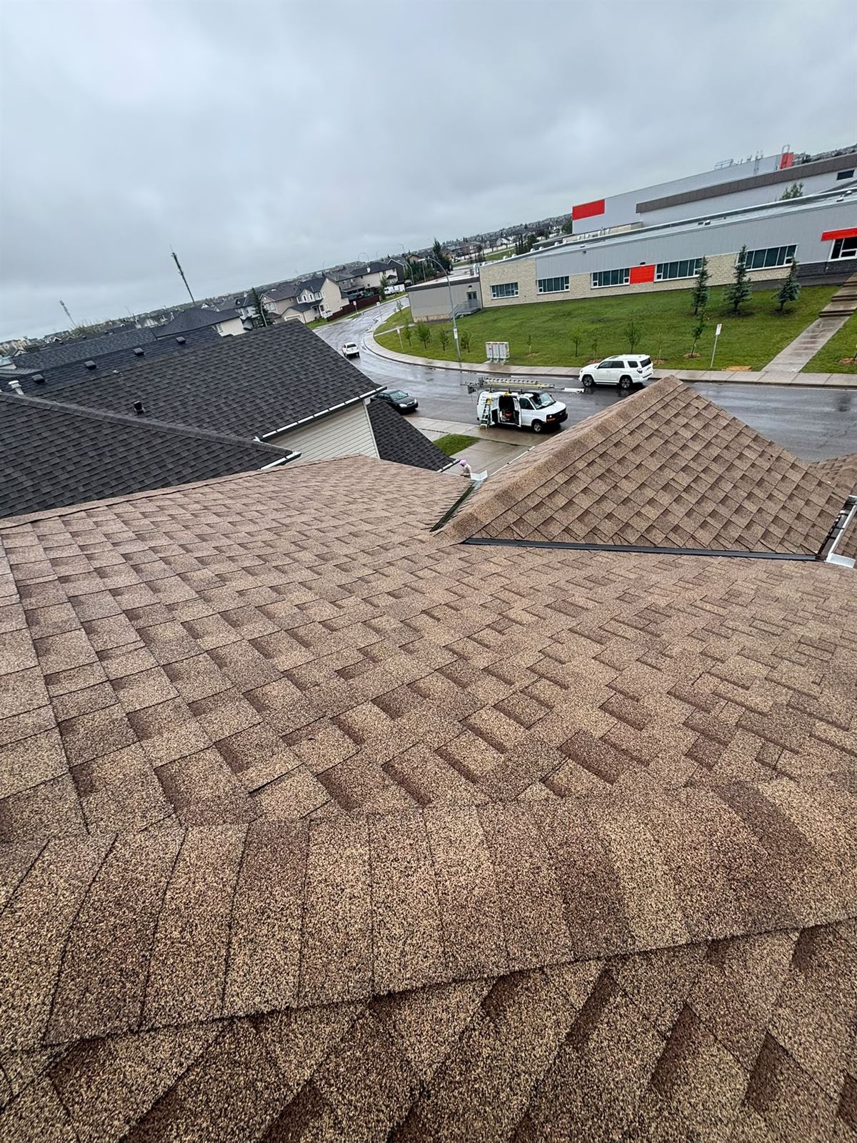 Completed roofing job with the work van and ladder on the street below