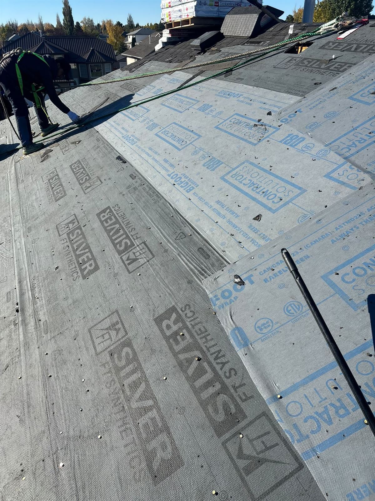 Tear-off and re-shingle in progress with new bundles staged on the roof