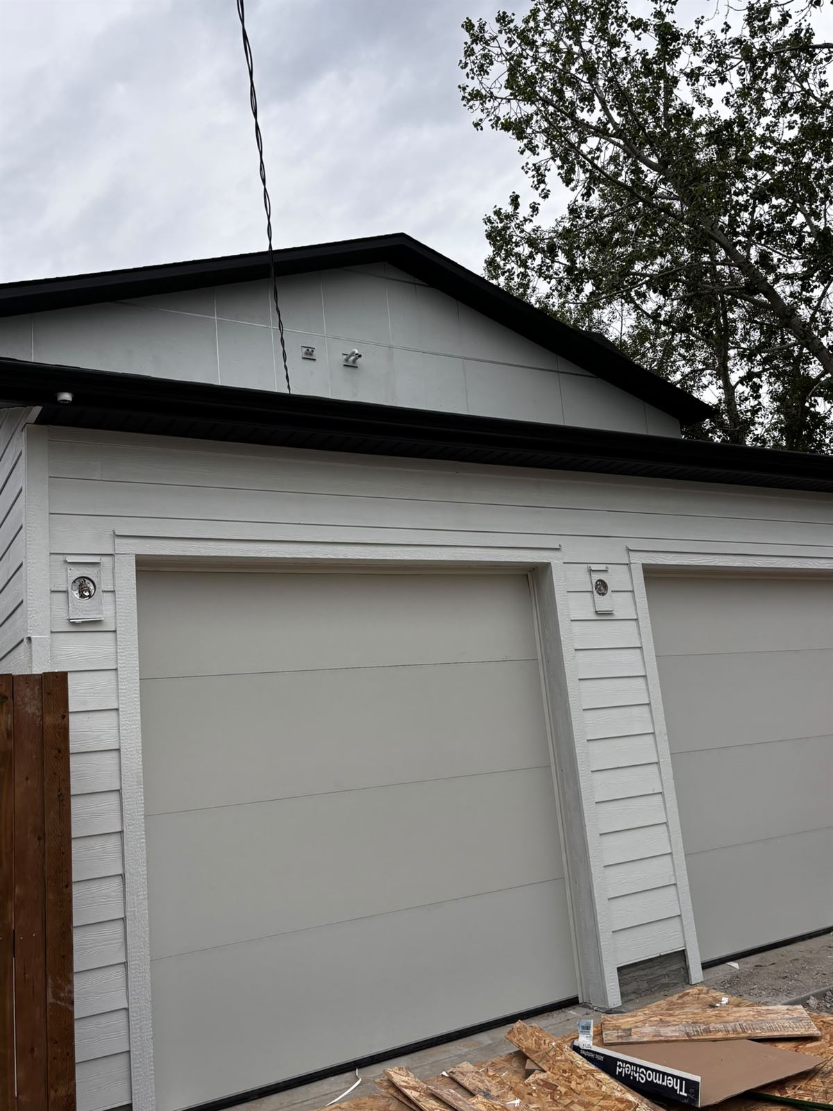Detached garage finished in white hardie siding with black fascia