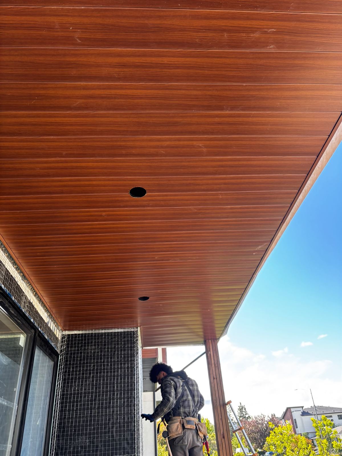 Wood-grain aluminum soffit installed under a modern balcony