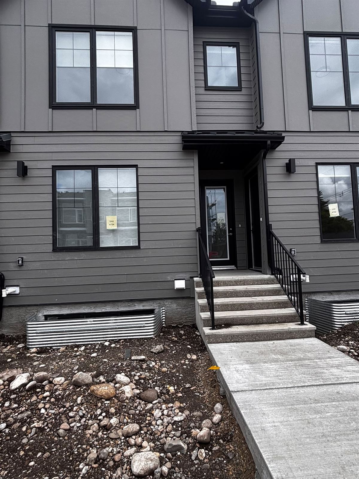 Finished townhome entrances with black railings and new concrete steps